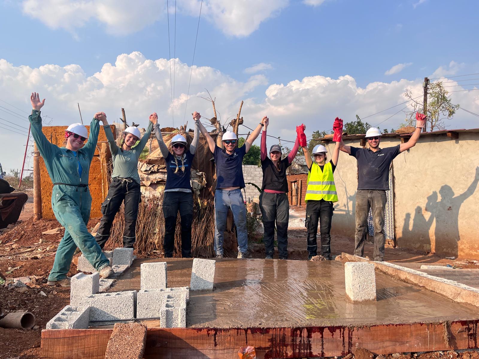 Gruppenfoto mit fertiger Bodenplatte auf der Baustelle des HoffnunsBAUer-Freiwilligeneinsatzes in Sambia 2026