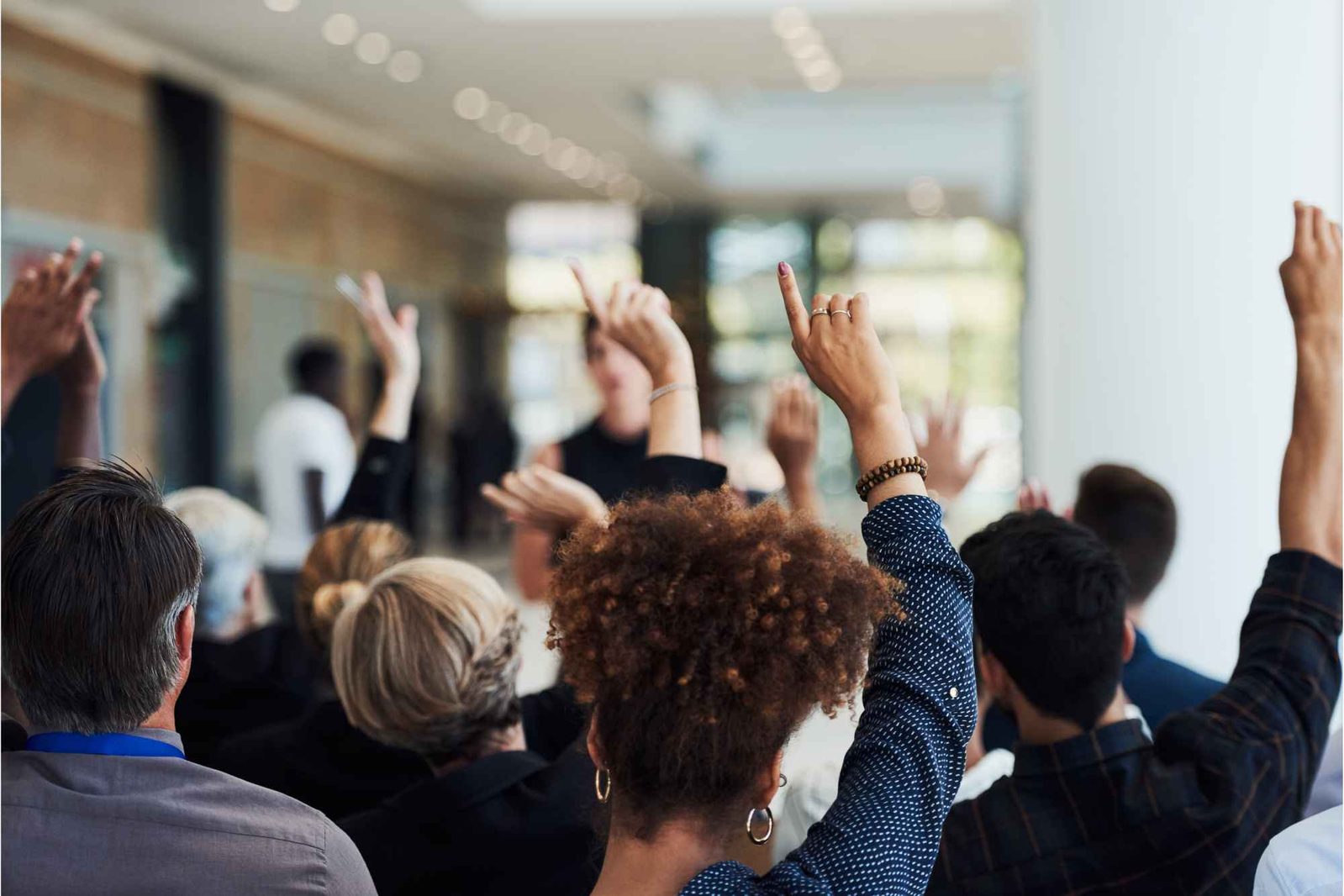 Menschen heben ihre Hände bei Eigentümerversammlung