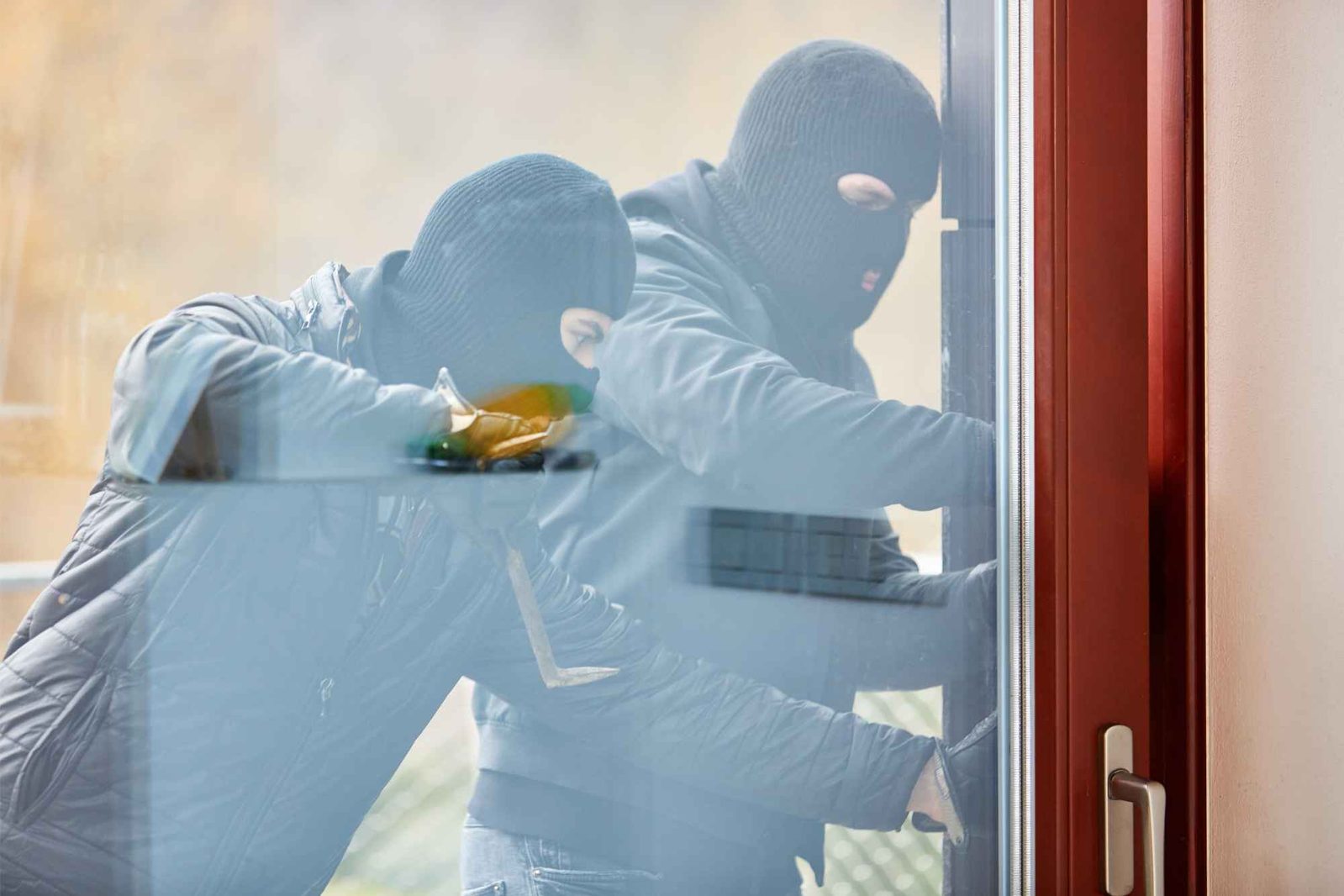 Zwei Einbrecher mit schwarzen Skimasken versuchen in ein Haus einzubrechen