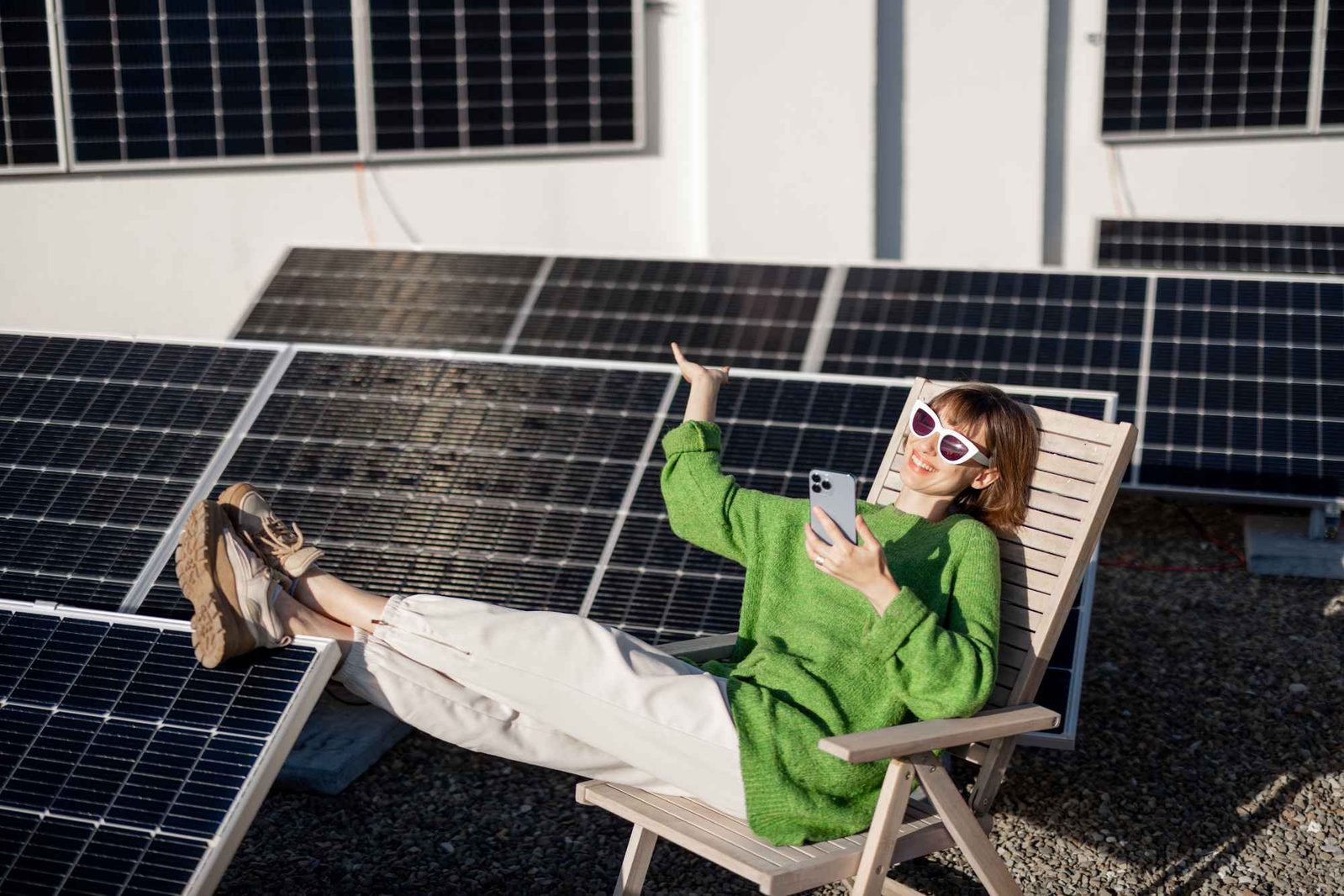 Frau mit Handy auf Liegestuhl vor Solarpanels