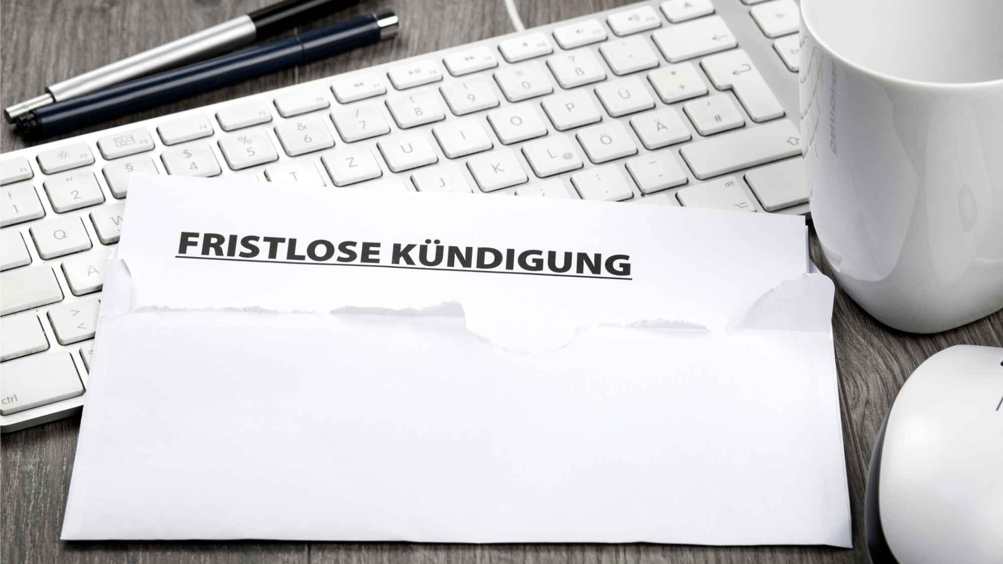 Briefumschlag mit fristloser Kündigung für Wohnung liegt auf Tastatur neben Maus und Kaffeetasse