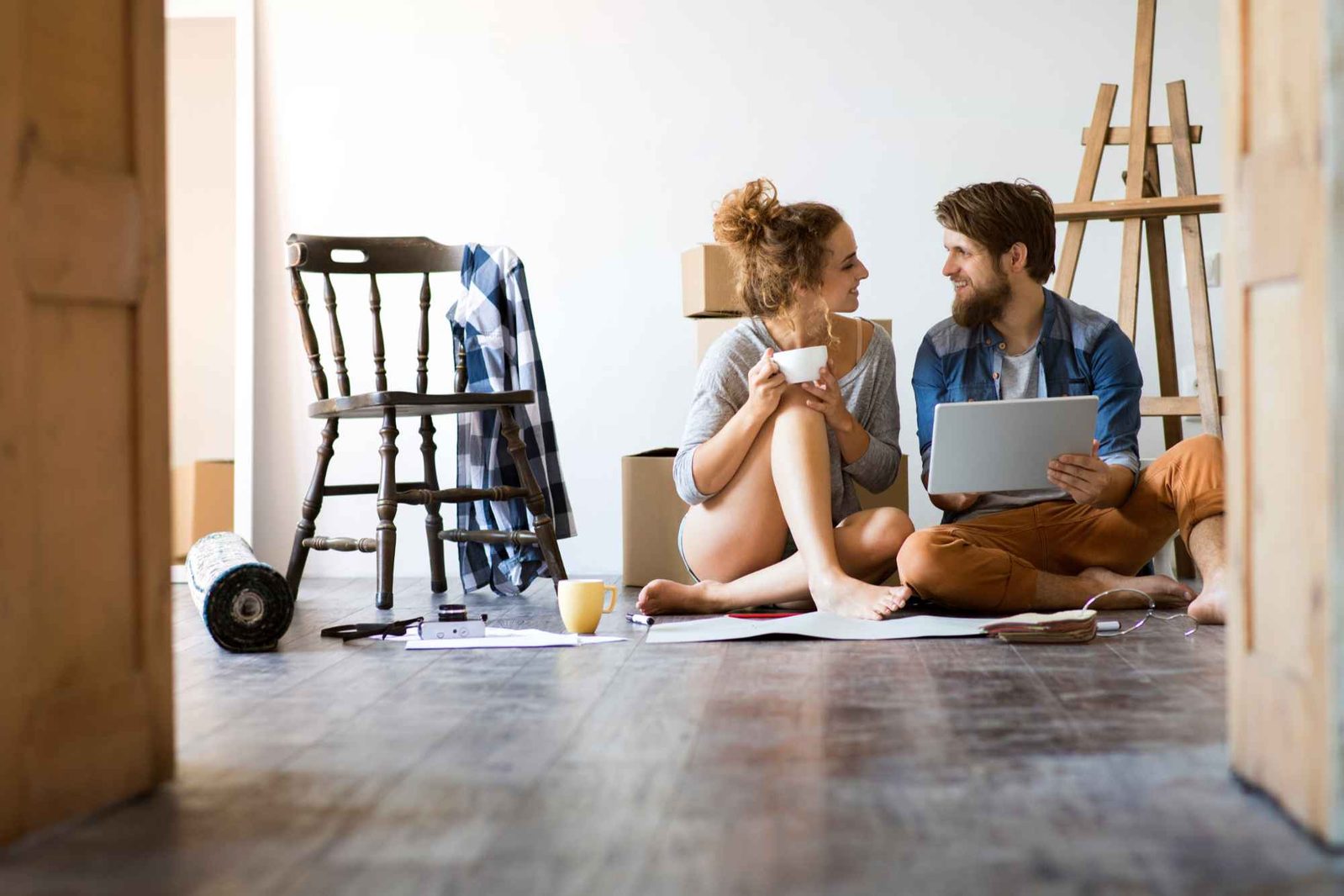 Paar mit Laptop sitzt auf Boden während Umzug
