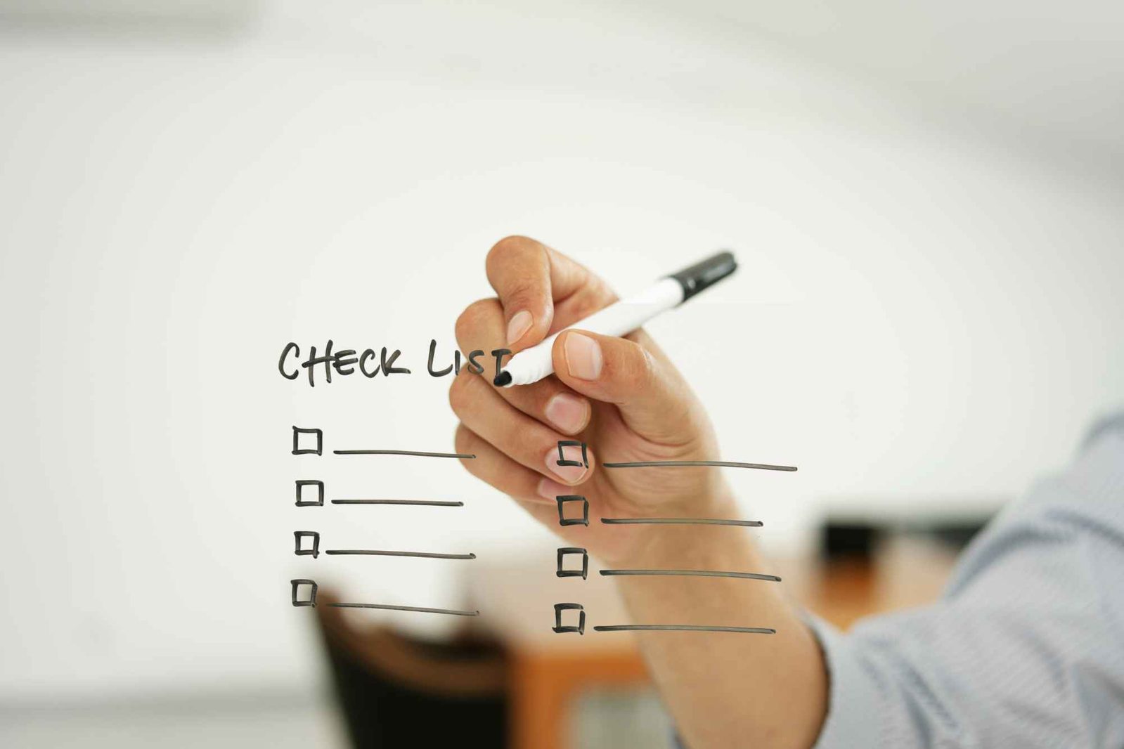 Hand mit Stift schreibt Checkliste auf durchsichtige Wand