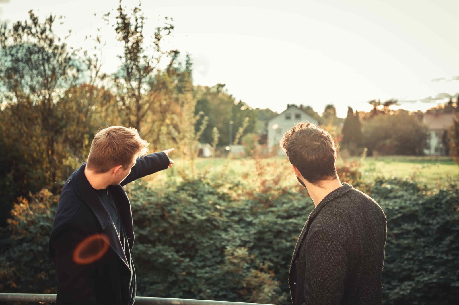 Zwei Männer gucken auf Immobilie mit Baugrundstück