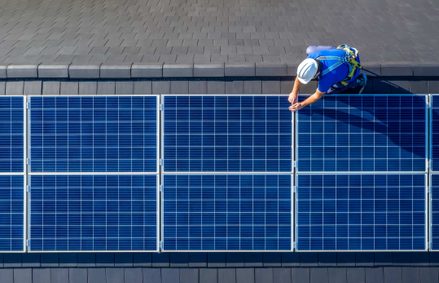 Erneuerbare Energien: Männlicher Ingenieur in blauem Anzug und Schutzhelm bei der Installation von Photovoltaik-Panel-System