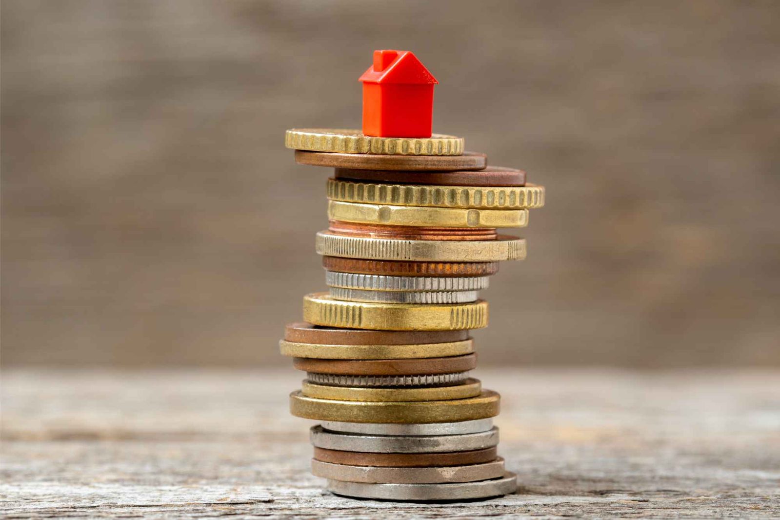 Rotes Spielzeughaus auf Stapel Geldmünzen