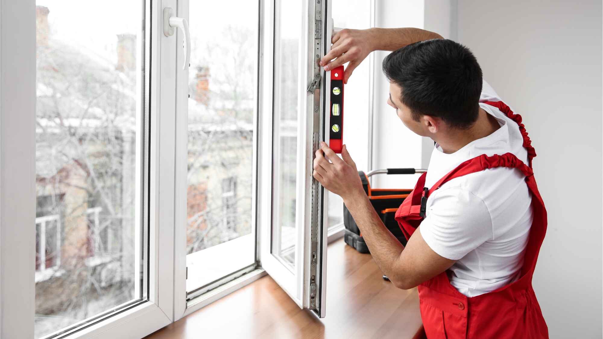 Handwerker überprüft Fenstereinbau mit einer Wasserwaage