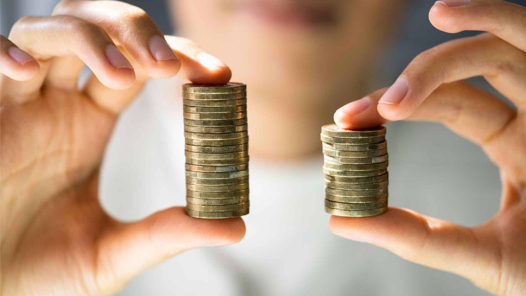 Mann hält in jeder Hand einen Münzstapel, der eine Stapel ist größer als der andere