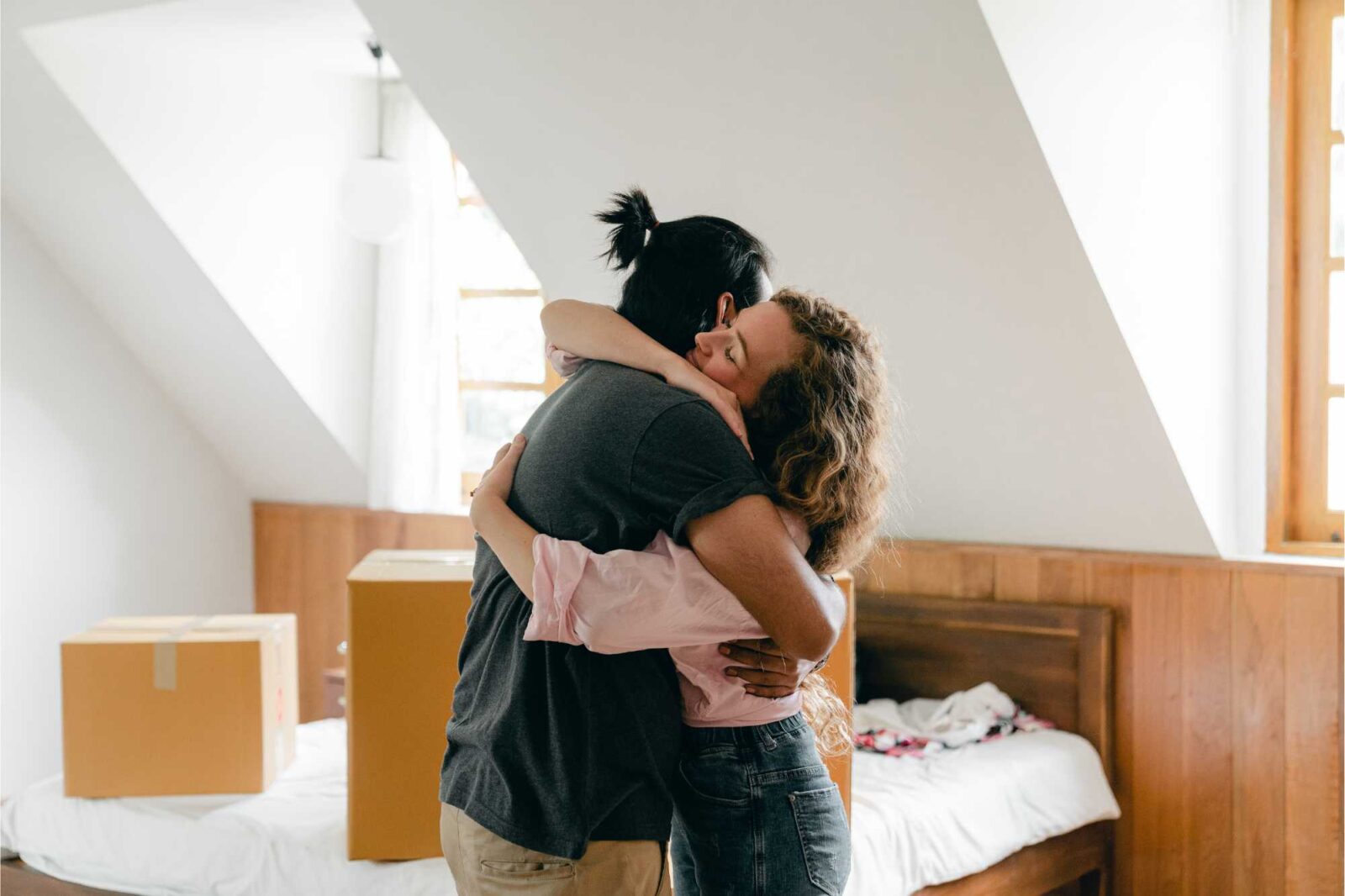 Pärchen umarmt sich in Wohnung, Umzugskartons im Hintergrund
