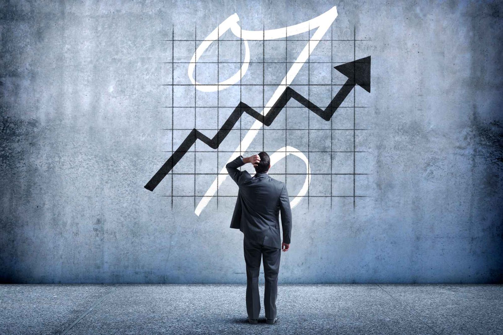 Mann steht mit Hand an Kopf vor Wand mit Grafik zu Zinsen für Baufinanzierung